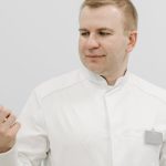 Man in white coat holding a pen, reflecting professionalism and focus.
