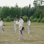 Group of soldiers practicing historical battlefield reenactment outdoors.